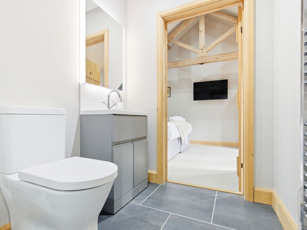 A bathroom with a toilet and sink looking towards a bedroom at The Saddlery in Norwich