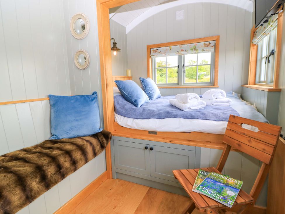 A bedroom with a bed and chair at Goose Whistle Hut in Foxham
