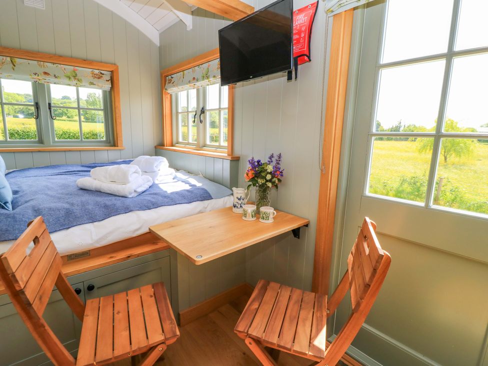 A sleeping area with a bed and table at Goose Whistle Hut in Foxham