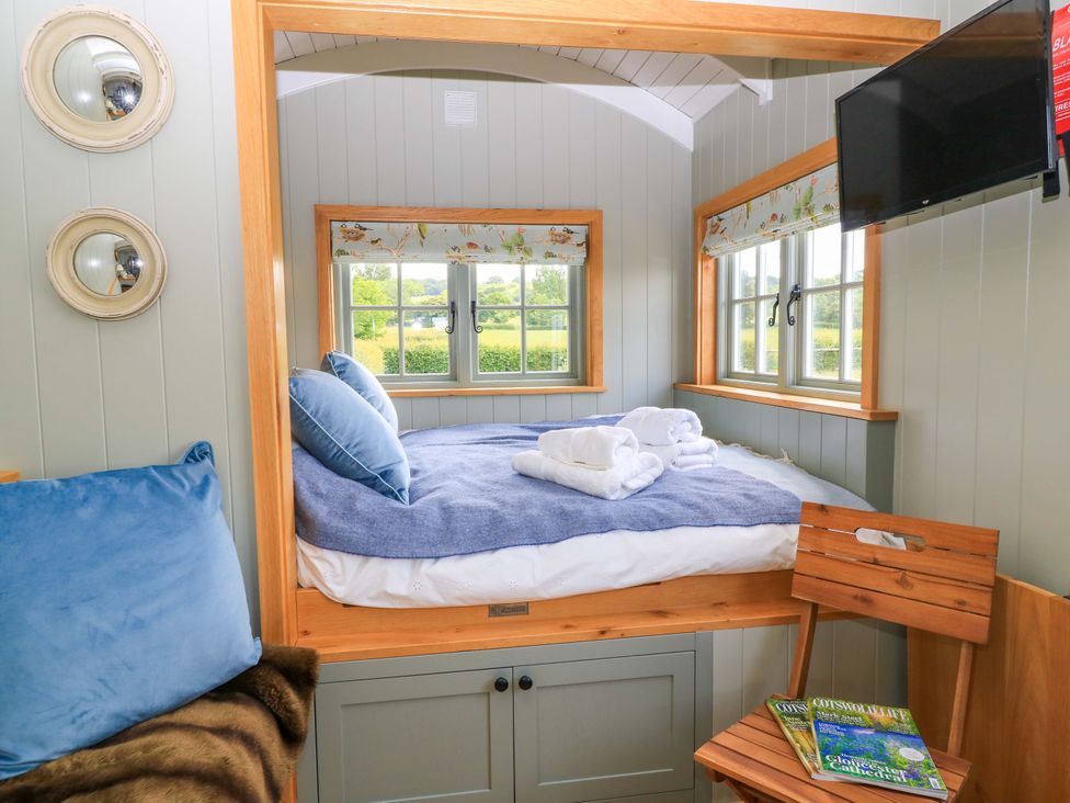 A bedroom with a bed and windows at Goose Whistle Hut in Foxham