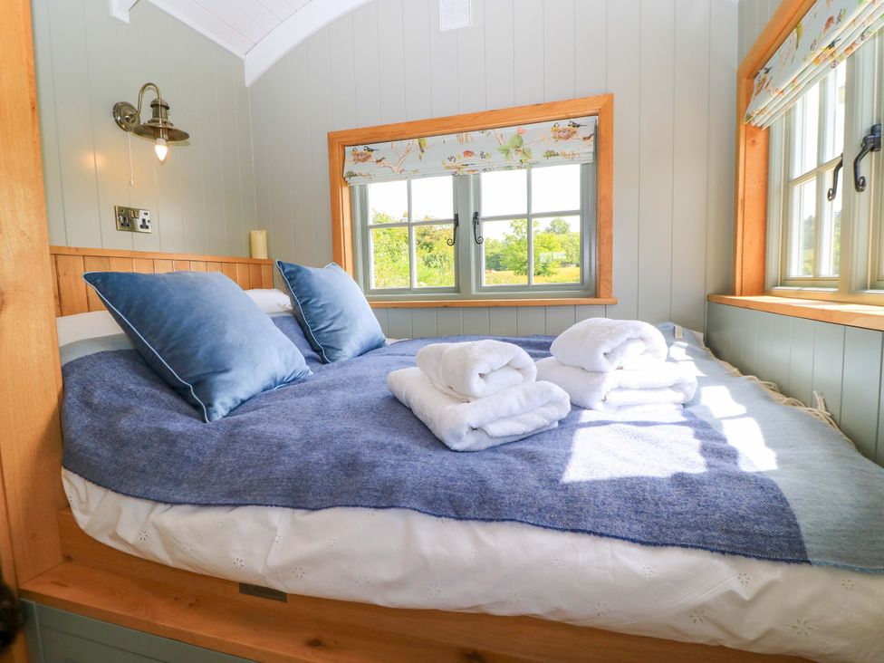A bedroom with a bed and pillows at Goose Whistle Hut in Foxham