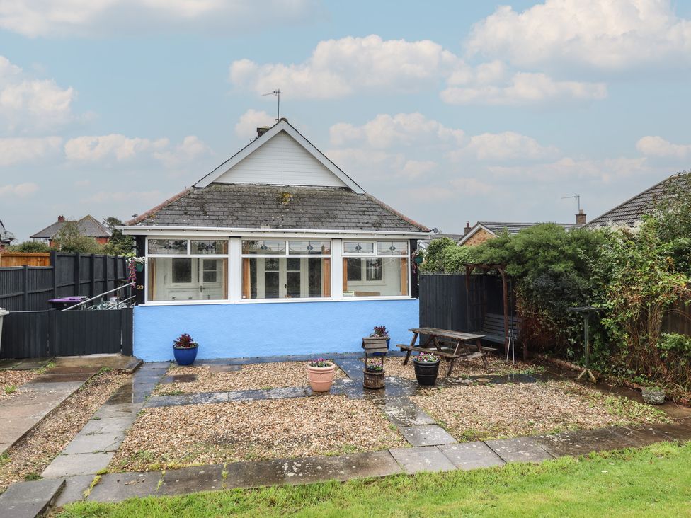 A garden with a bungalow and gravel area at Orby Cottage in Chapel St Leonards