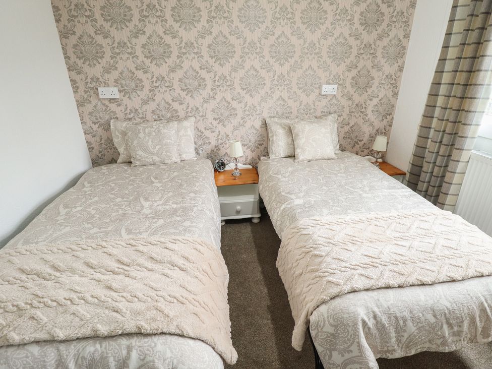 A bedroom with two single beds and lamps at Orby Cottage in Chapel St Leonards