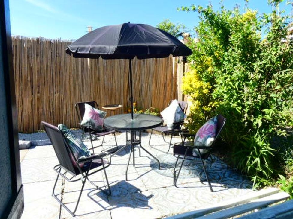 A garden with a table and chairs under an umbrella at Orby Cottage, Chapel St Leonards