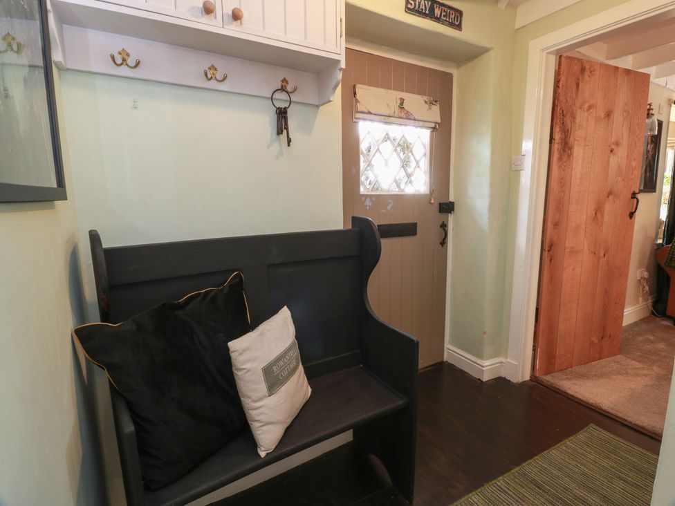 A hallway with a bench and coat hooks at Rowantree Cottage in Kelso