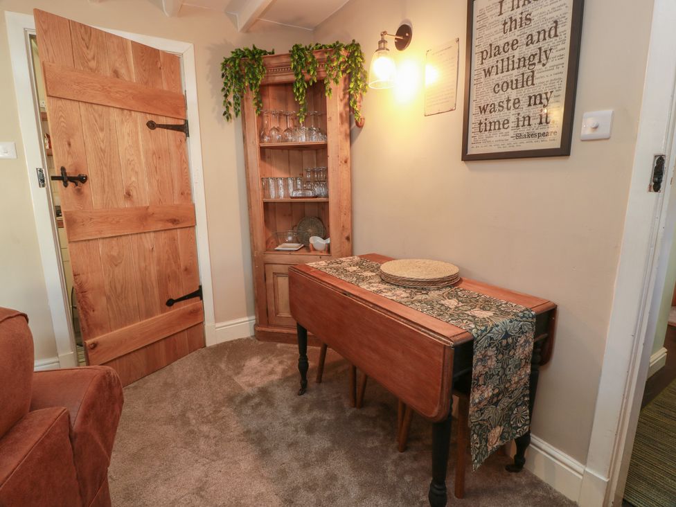A dining room with a table and glassware in a cabinet at Rowantree Cottage in Kelso