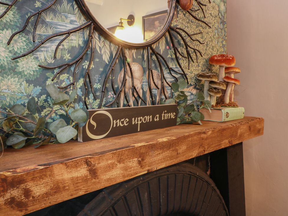 A living room with a decorative shelf and mirror at Rowantree Cottage in Kelso