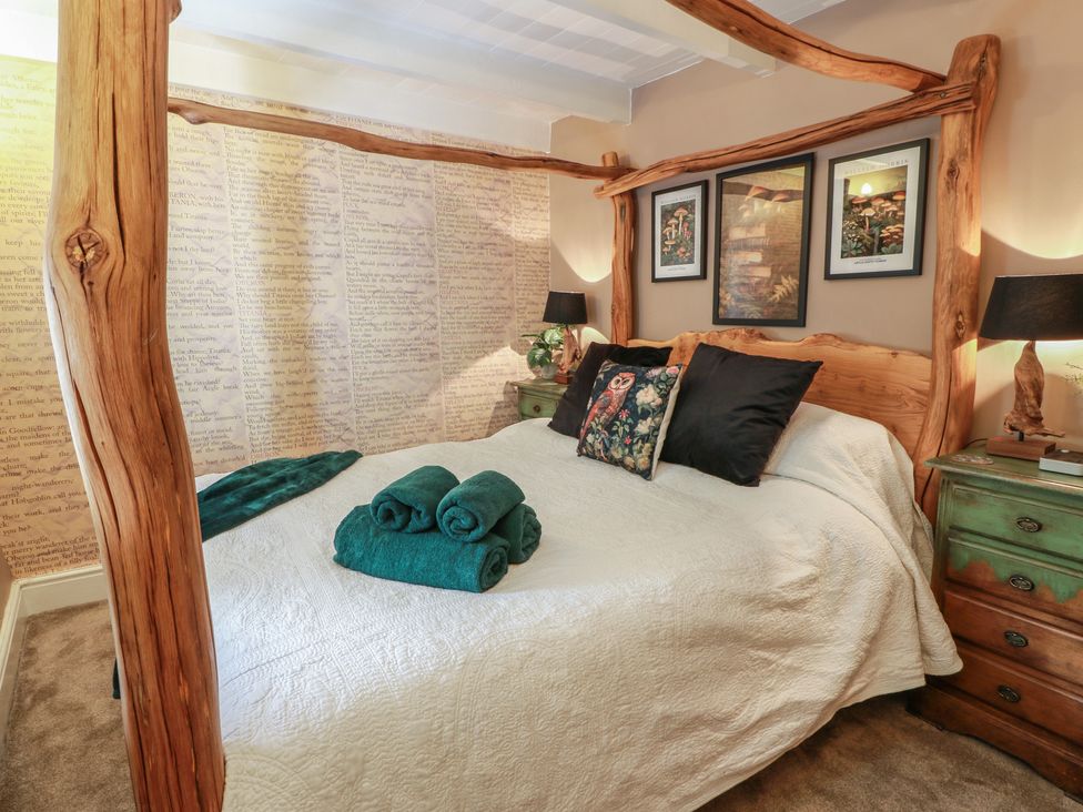 A bedroom with a four-poster bed and art on the wall at Rowantree Cottage in Kelso