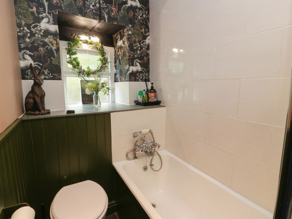 A bathroom with a bathtub and decorative items at Rowantree Cottage in Kelso