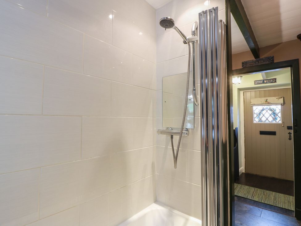 A shower with a glass screen and tiled walls at Rowantree Cottage in Kelso