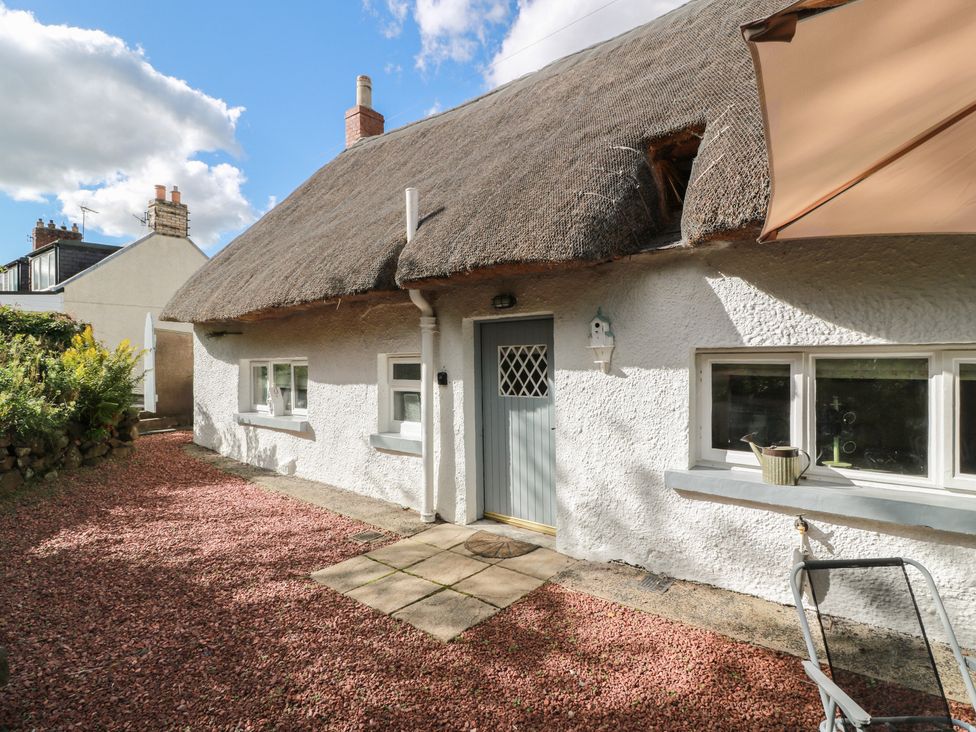An outdoor view of a cottage with a thatched roof at Rowantree Cottage in Kelso