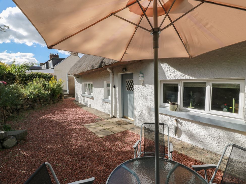 An outdoor patio area with a table and chairs under an umbrella at Rowantree Cottage in Kelso