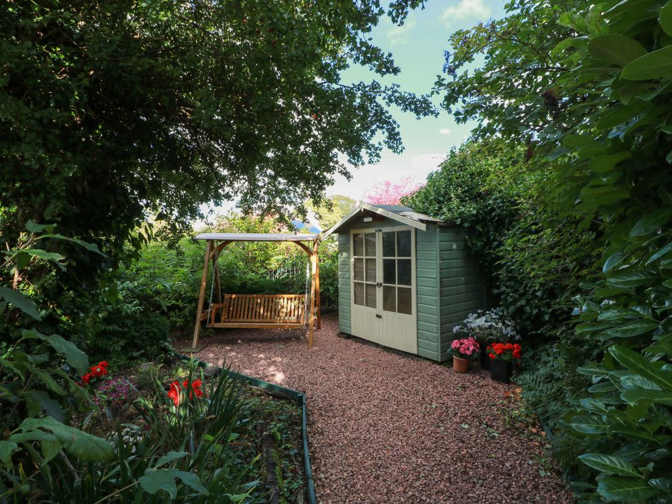 A garden featuring a swing and a shed at Rowantree Cottage in Kelso