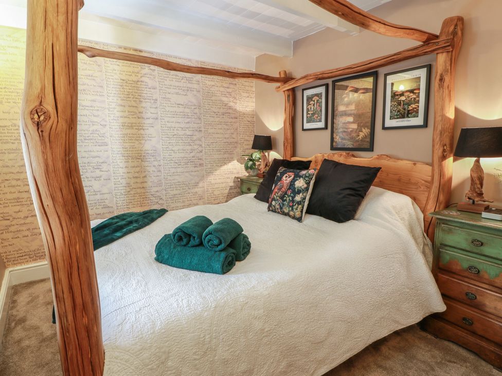 A bedroom with a canopy bed and towels on the bed at Rowantree Cottage in Town Yetholm And Kirk Yetholm
