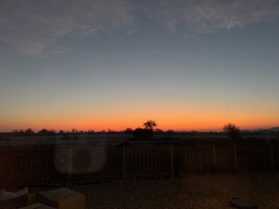 A sunset view with trees and a fence at Number 3 The Barn House in Woodham