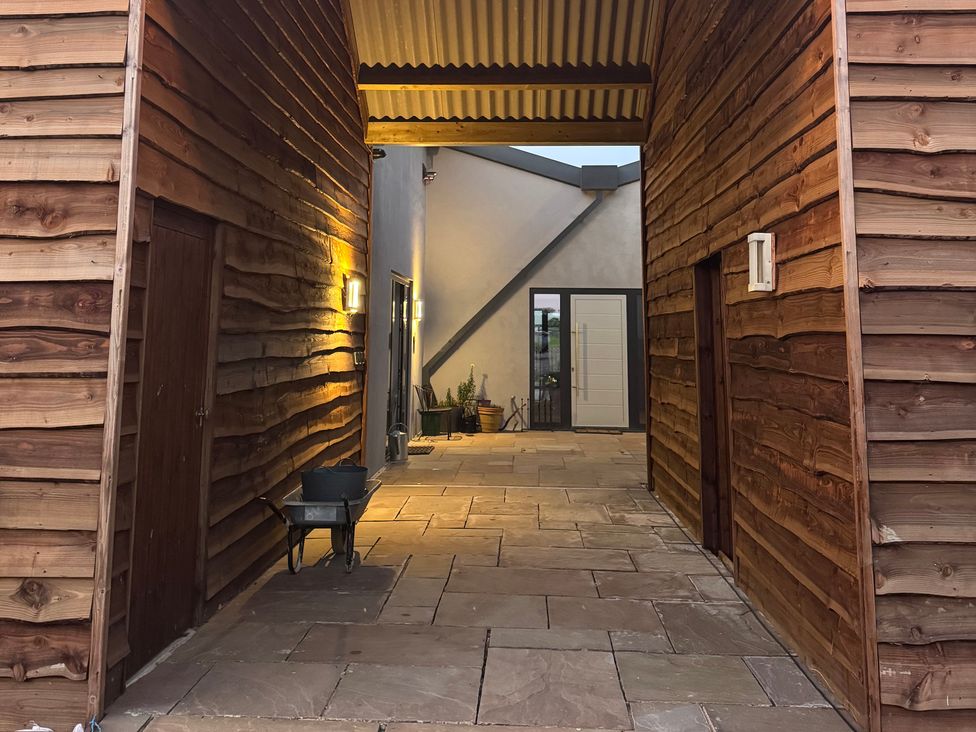 An outdoor area with a paved walkway and wooden walls at Number 3 The Barn House Woodham