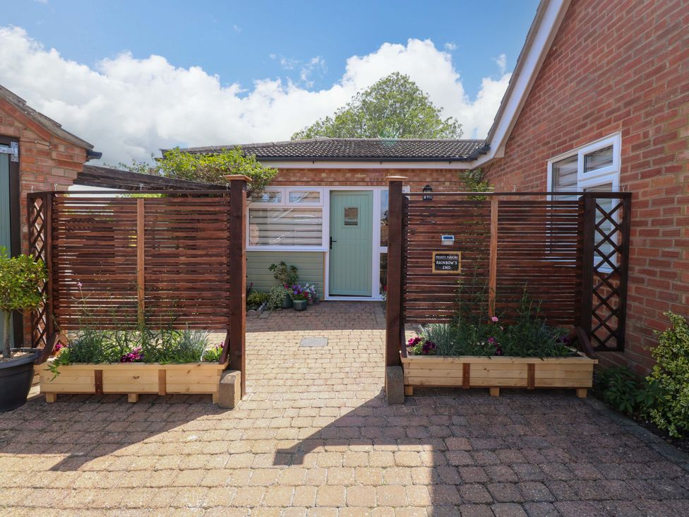 An entrance with a fence and plant beds at Rainbow's End in Swanton Morley