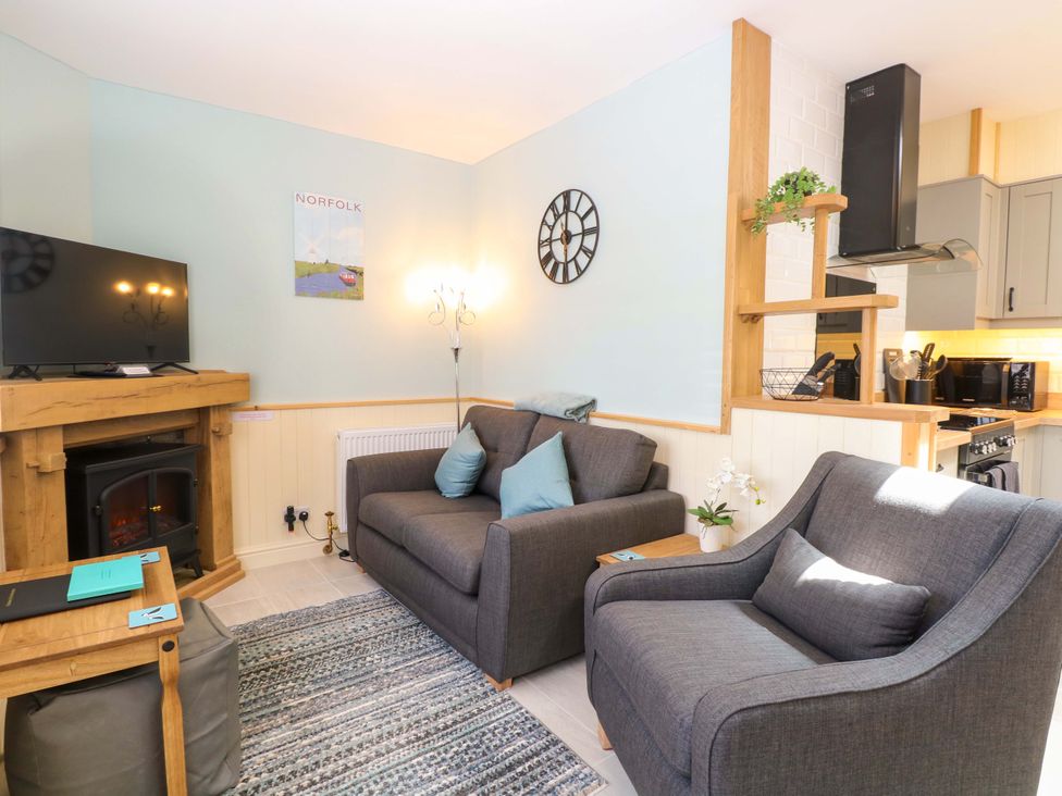 A living room with a tv, sofa, and fireplace at Rainbow's End in Swanton Morley