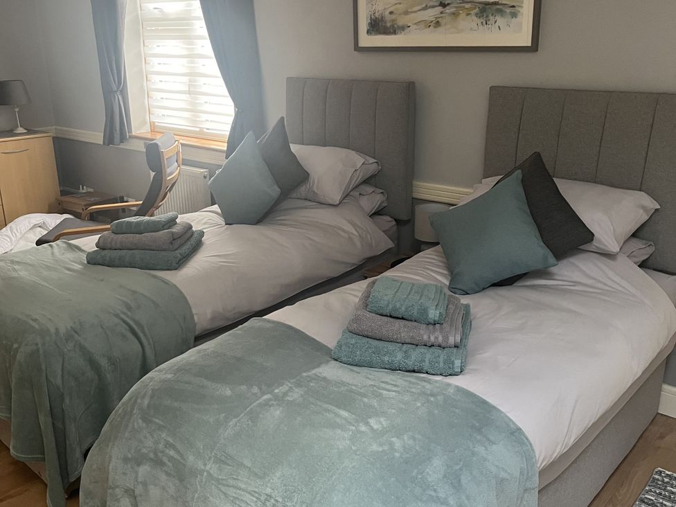 A bedroom with two beds and a chair at Rainbow's End in Swanton Morley