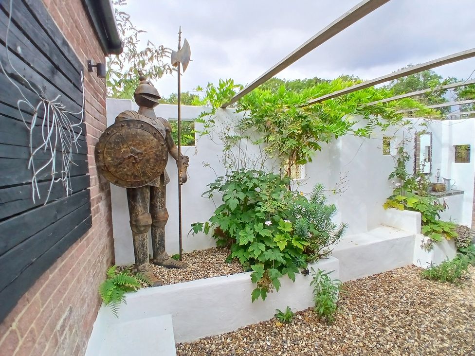 A garden with a statue of a knight and various plants at The Corner House Ufford near Woodbridge