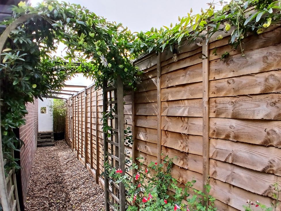 A garden path with a wooden fence and plants at The Corner House in Ufford near Woodbridge
