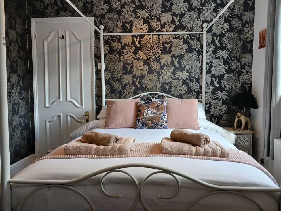 A bedroom featuring a canopy bed with linens and decorative pillows at The Corner House in Ufford near Woodbridge
