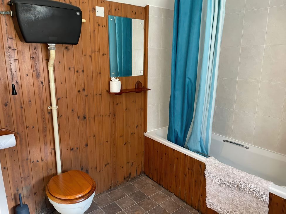A bathroom with a toilet, bath tub, and a mirror at Vinney Cottage in Owermoigne