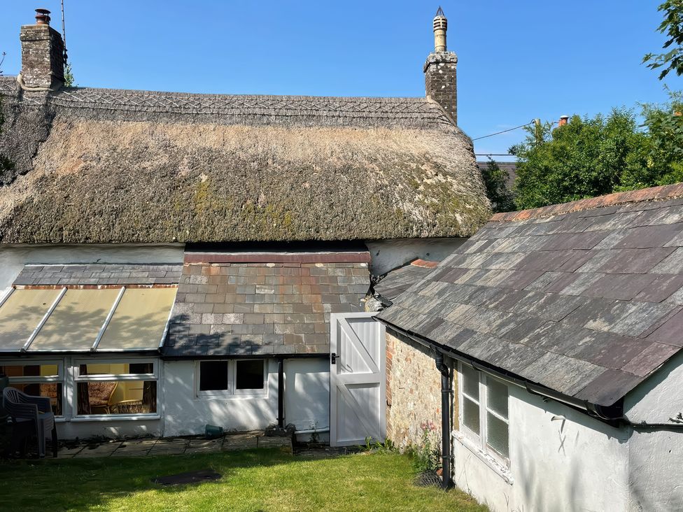 A building with a thatched roof and slate roofs at Vinney Cottage in Owermoigne