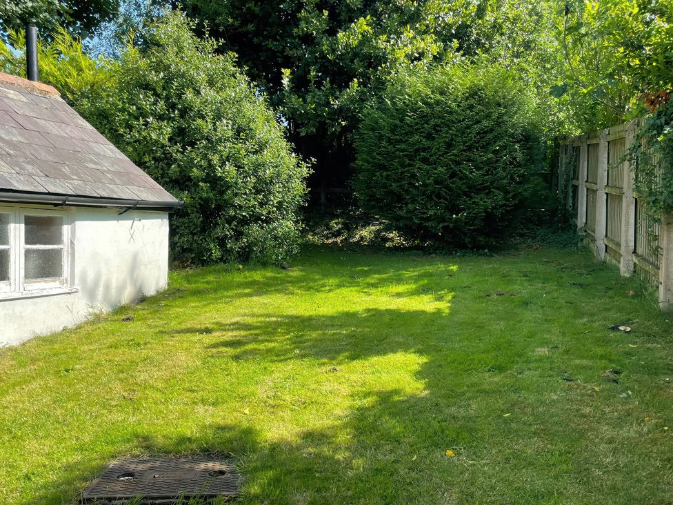 A garden with grass and bushes at Vinney Cottage in Owermoigne