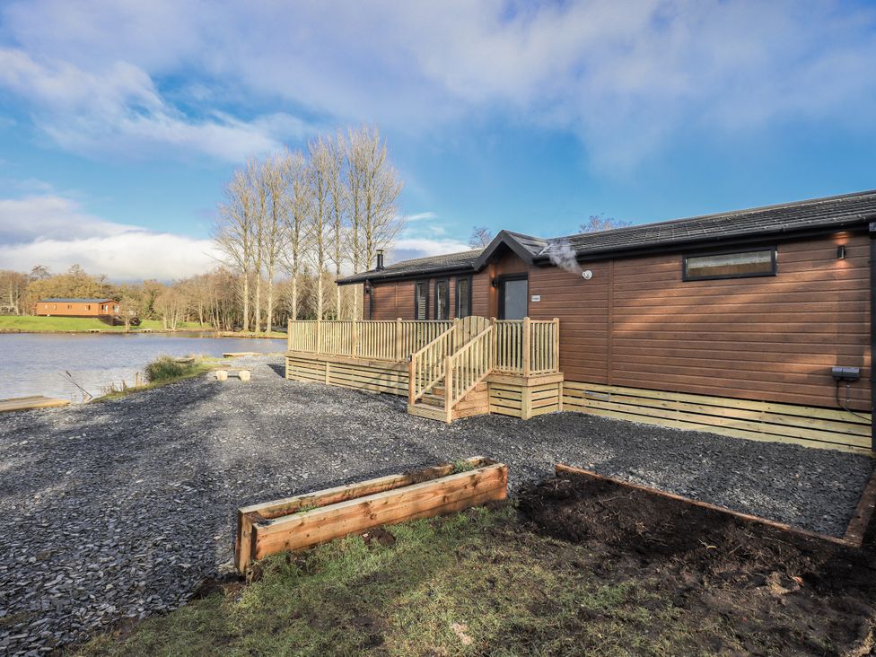 A lodge by the lake with decking and gravel area at Lakeside Lodge Bowland Lakes Leisure Village near Garstang