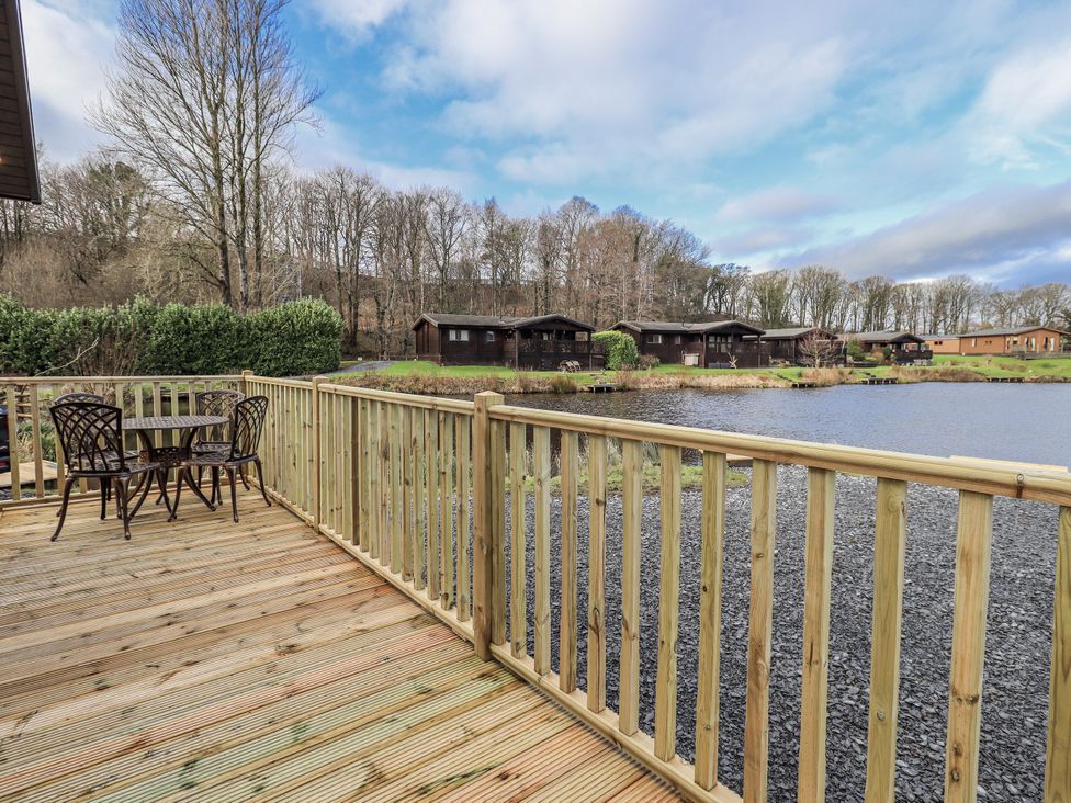 An outdoor area with a table and chairs by a lake at Lakeside Lodge Bowland Lakes Leisure Village near Garstang