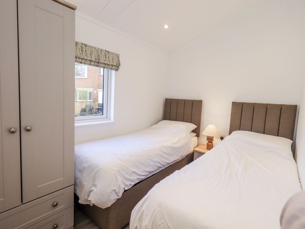 A bedroom with two single beds and a wardrobe at Lakeside Lodge Bowland Lakes Leisure Village near Garstang