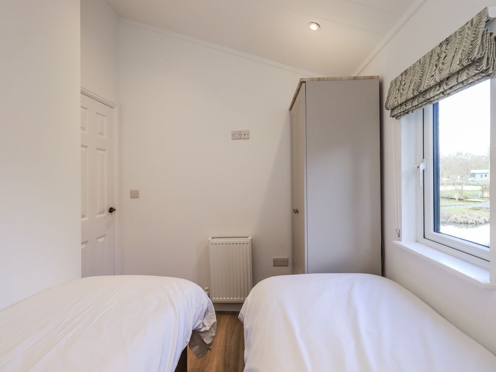 A bedroom with two beds and a wardrobe at Lakeside Lodge near Bowland Lakes Leisure Village