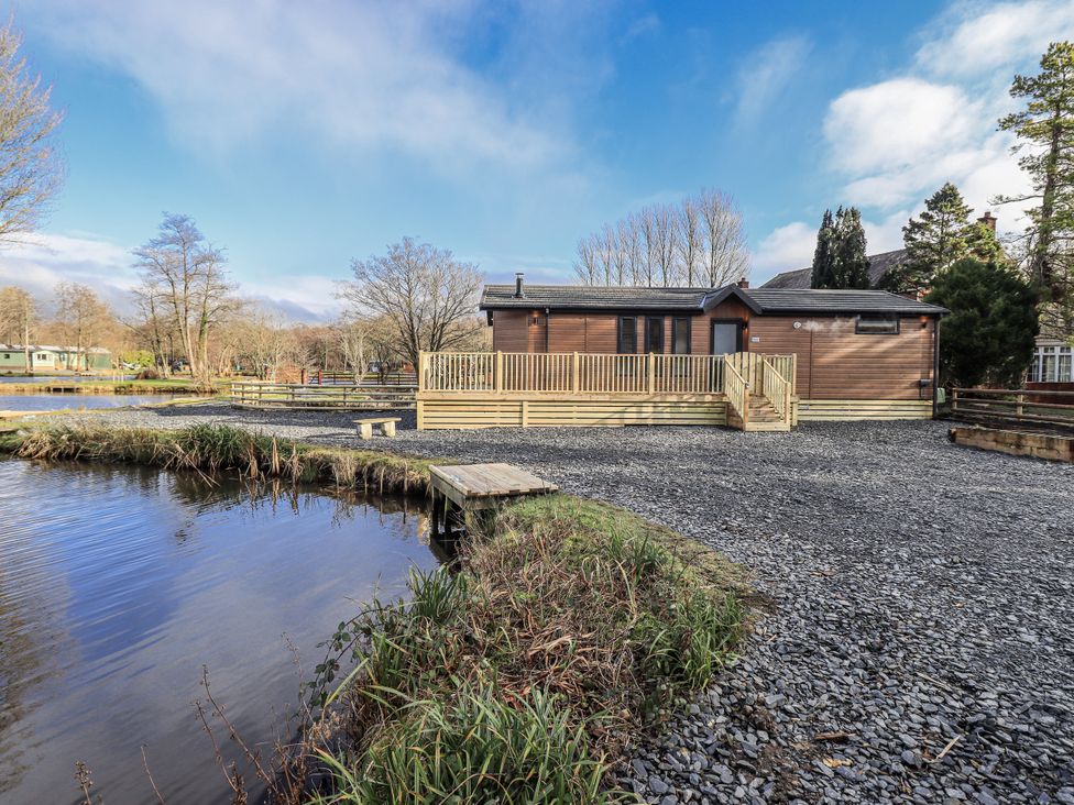 A lodge with a deck and pond at Lakeside Lodge Bowland Lakes Leisure Village near Garstang