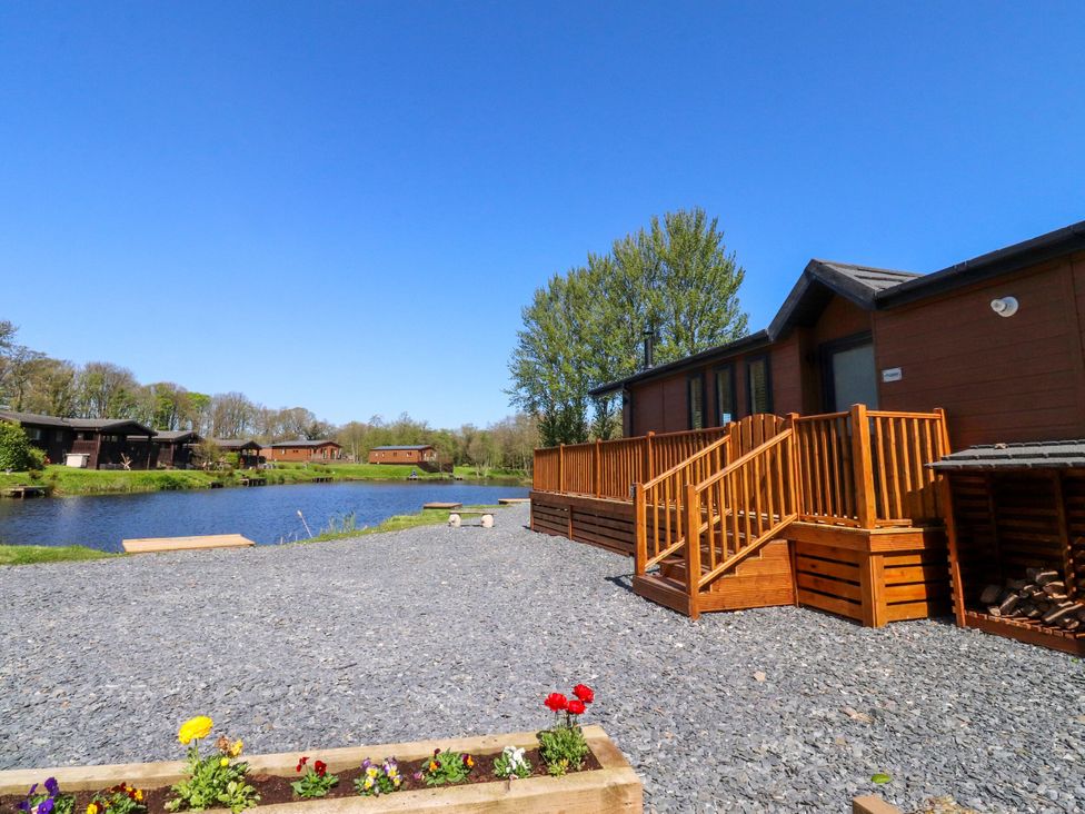 An outdoor area with a lodge and deck near a river at Lakeside Lodge Bowland Lakes Leisure Village near Garstang