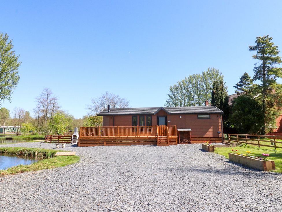 A house with a deck and gravel driveway at Lakeside Lodge near Bowland Lakes Leisure Village