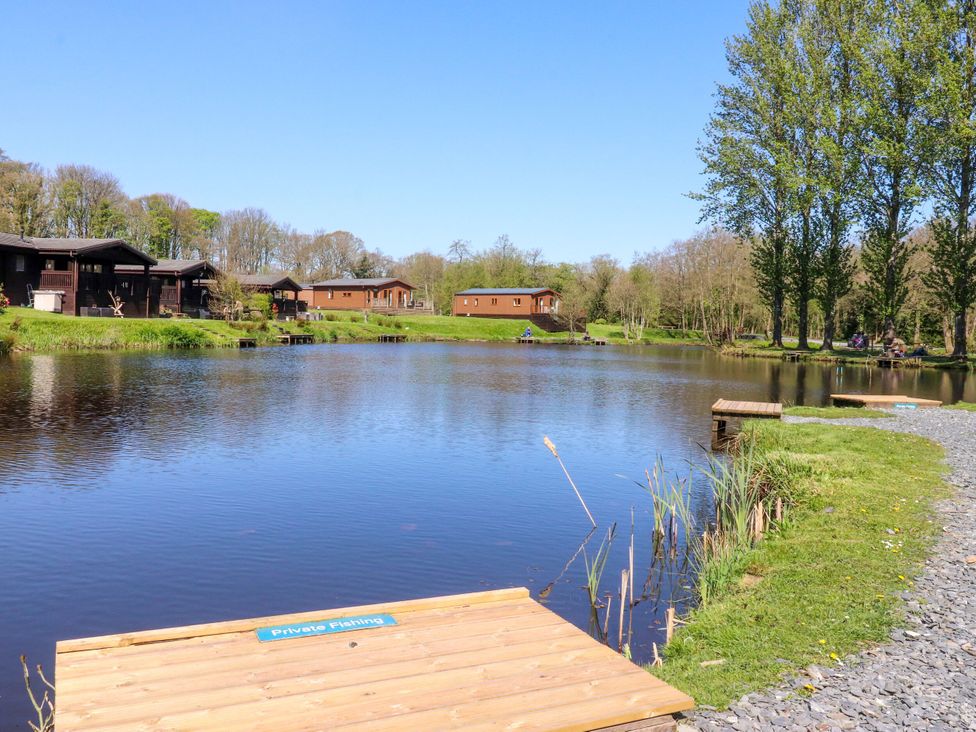 A lake with cabins and a fishing dock at Lakeside Lodge Bowland Lakes Leisure Village near Garstang
