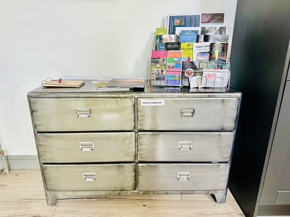 A games cupboard with magazines and a notebook at Parlour Barn in Leek