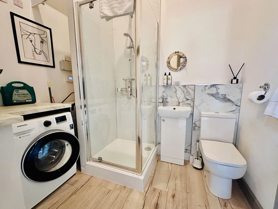 A bathroom with shower, toilet, sink and washing machine at Parlour Barn in Leek