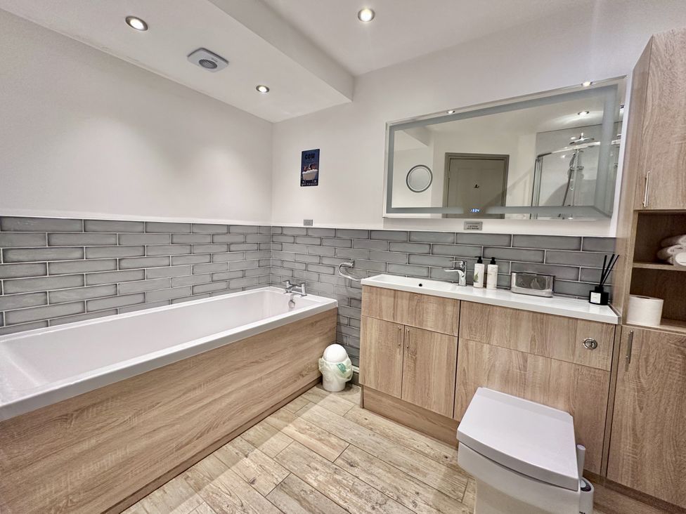 A bathroom with a bathtub, sink and toilet at Parlour Barn in Leek