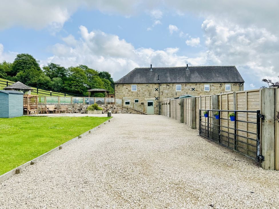 An outdoor space with a stone house and seating area at Parlour Barn in Leek