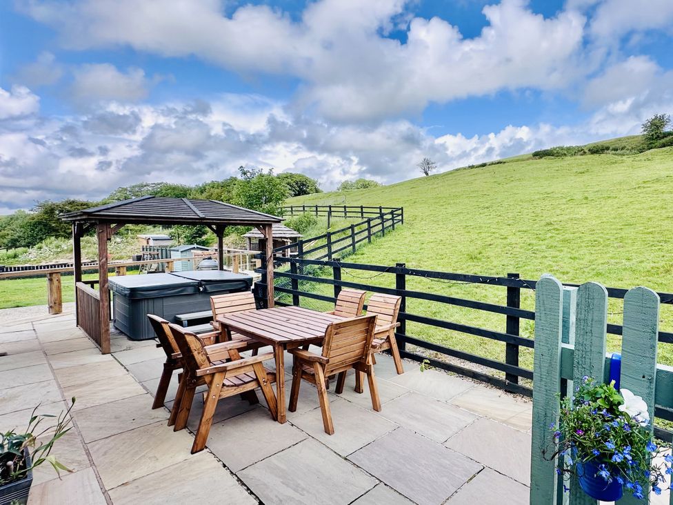 A patio with a hot tub and dining set at Parlour Barn in Leek