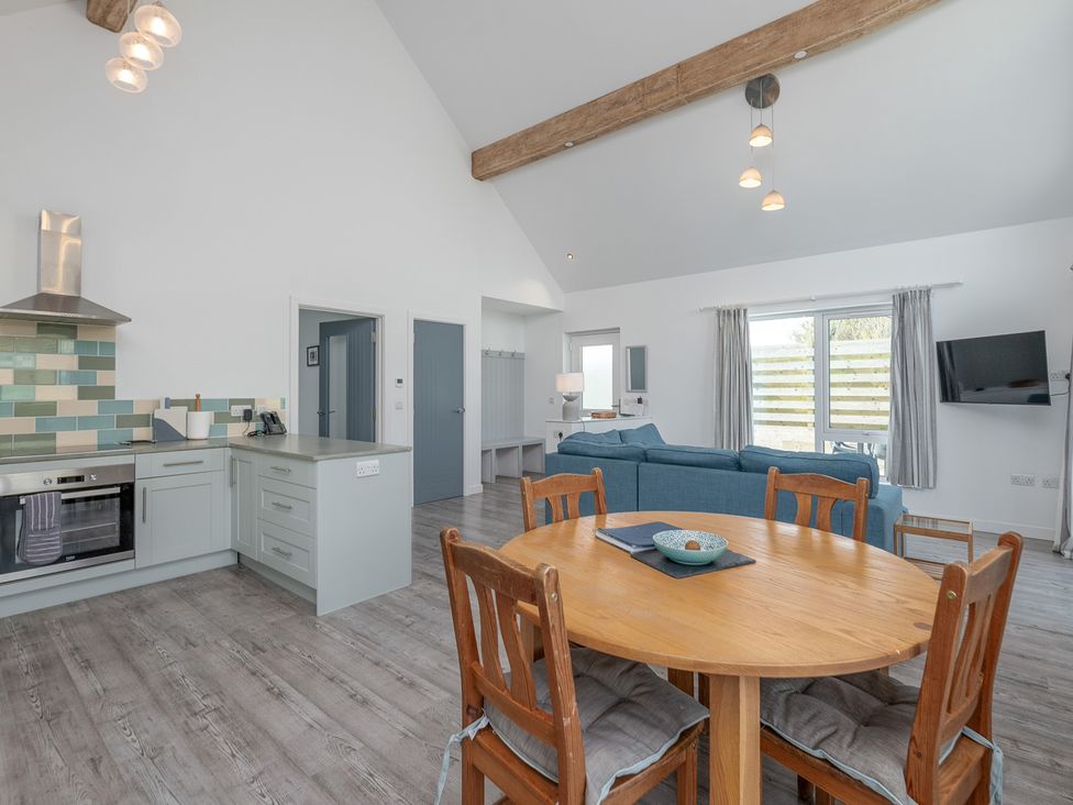 An open plan kitchen and living area with a dining table at Moranedd Bach in Holyhead