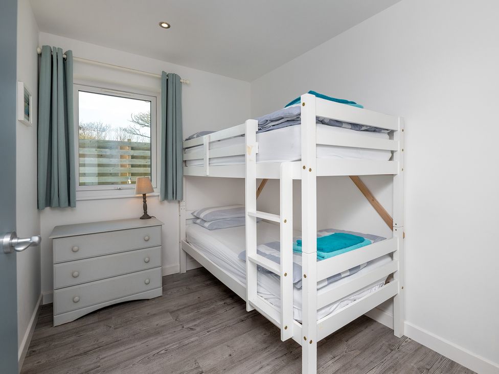 A bedroom with a bunk bed and dresser at Moranedd Bach in Holyhead