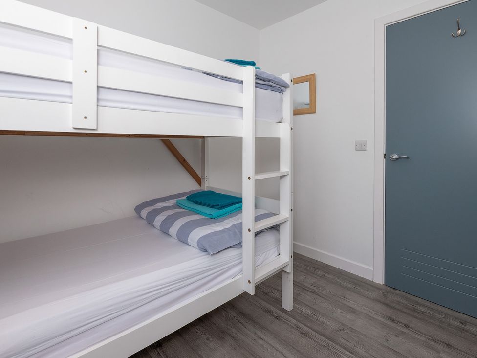 A bedroom with a bunk bed and towels at Moranedd Bach in Holyhead