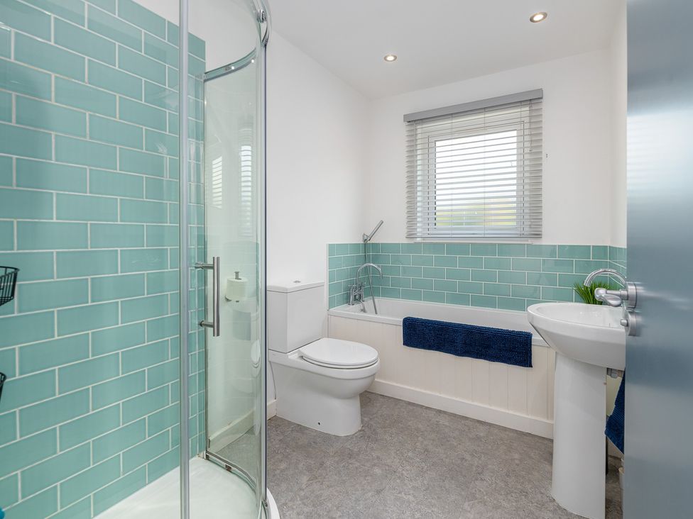 A bathroom with a shower, toilet, bathtub, and sink at Moranedd Bach in Holyhead