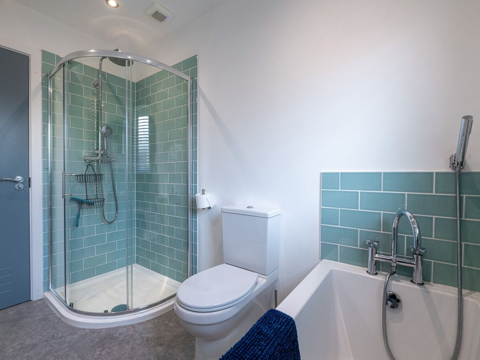 A bathroom with shower, toilet, and bathtub at Moranedd Bach in Holyhead