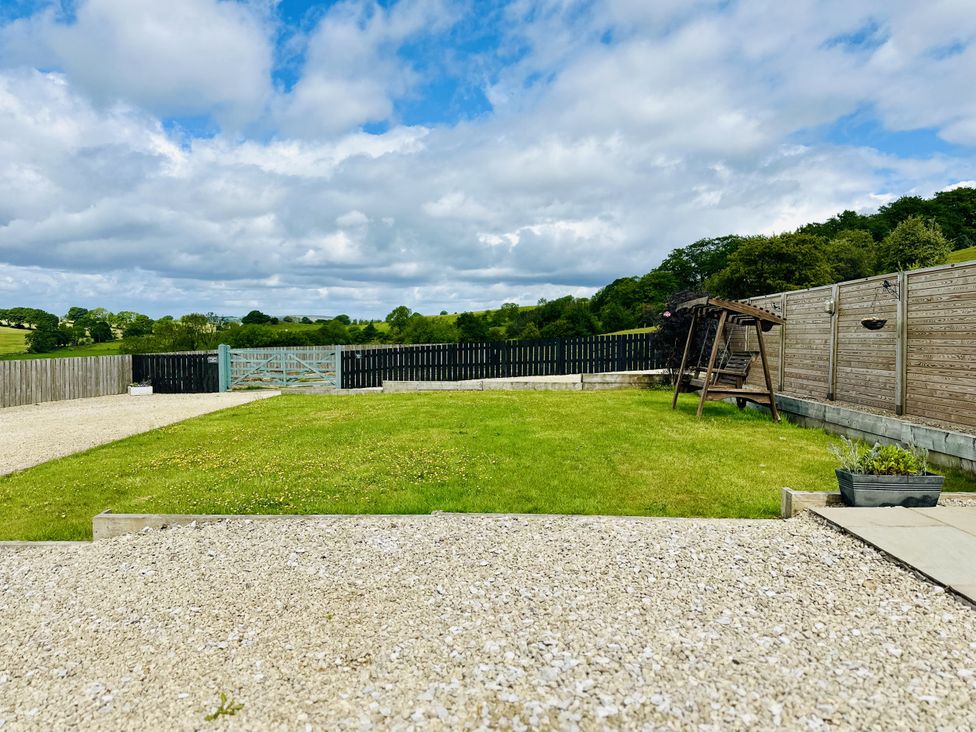 A garden with a grass lawn a wooden swing fence and gravel at Pastures Barn Bradnop near Leek