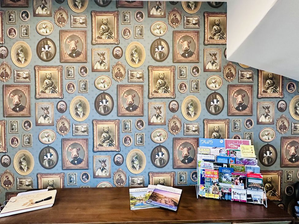 A decorative wall with portraits and a table displaying brochures at Pastures Barn in Bradnop near Leek