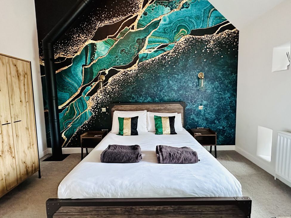 A bedroom with a bed and wall art at Pastures Barn in Bradnop near Leek